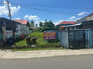 Lahan dengan papan bertuliskan tanah dijual di tepi jalan